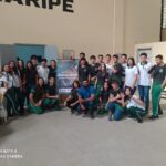 Principais Momentos do Dia da Matemática Malbatemática no Ceará 27 turma de alunos ao lado de cartaz do evento