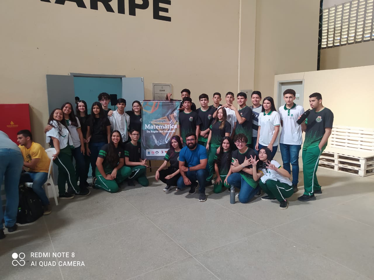 Principais Momentos do Dia da Matemática Malbatemática no Ceará 27 turma de alunos ao lado de cartaz do evento