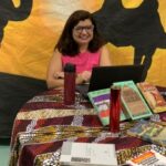 Foto da professora Cristiane Coppe sentada à mesa